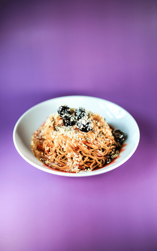 Eiscafé Venezia - Spaghetti Nero Eis auf lila Hintergrund